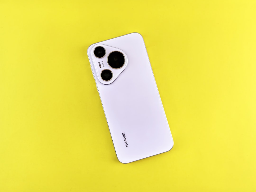 A white smartphone rests on a yellow background.