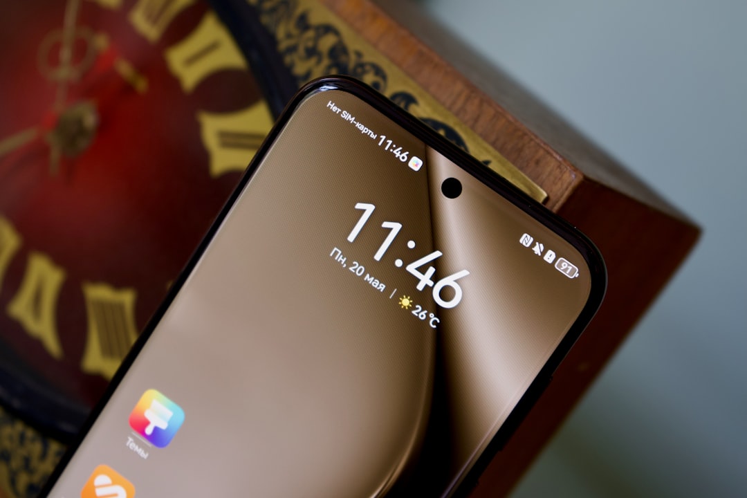 A close up of a cell phone near a clock
