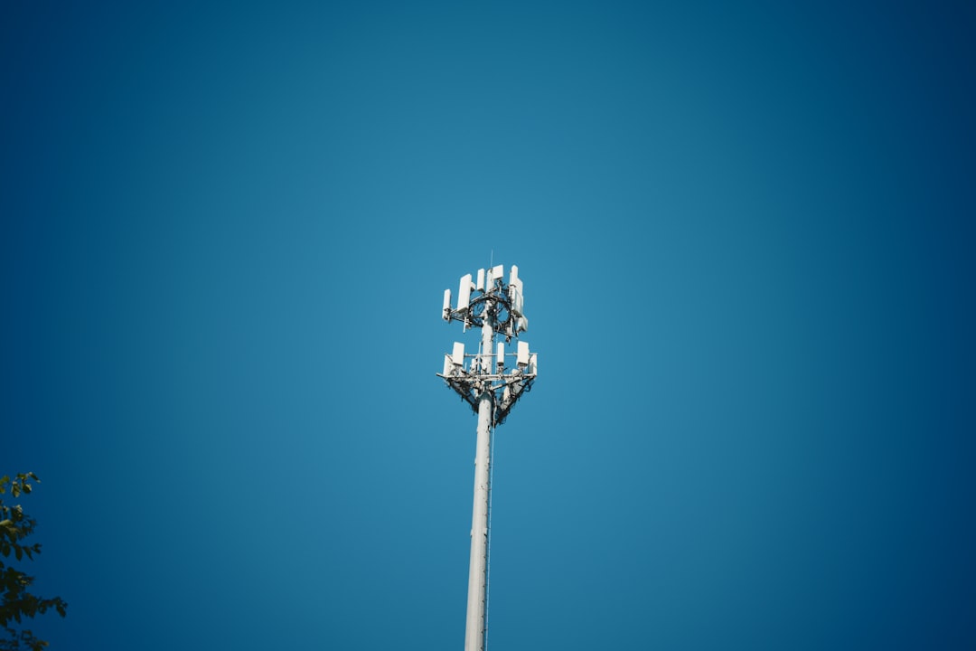 A tall cell tower stands against a clear blue sky.